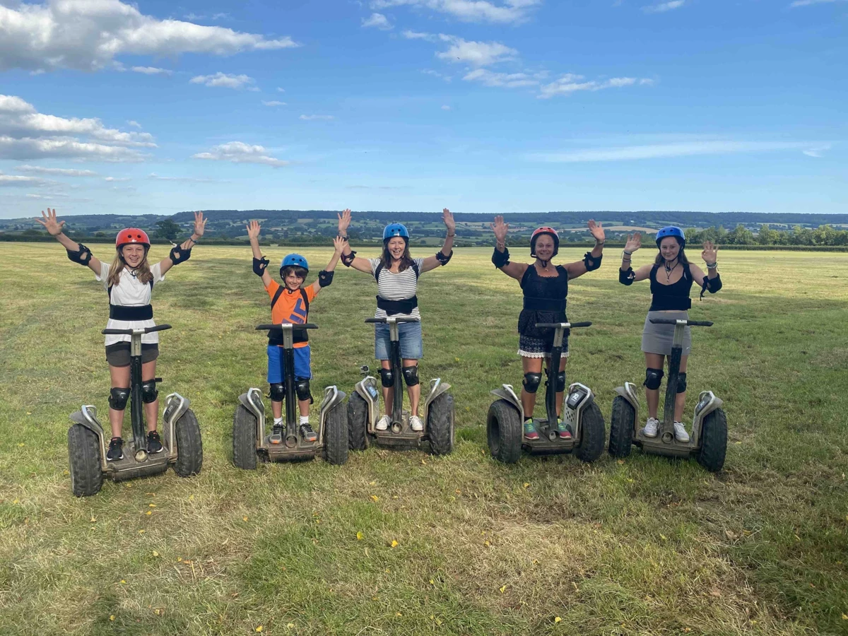 A group of friends on Segways raising their hands on the Escot Estate